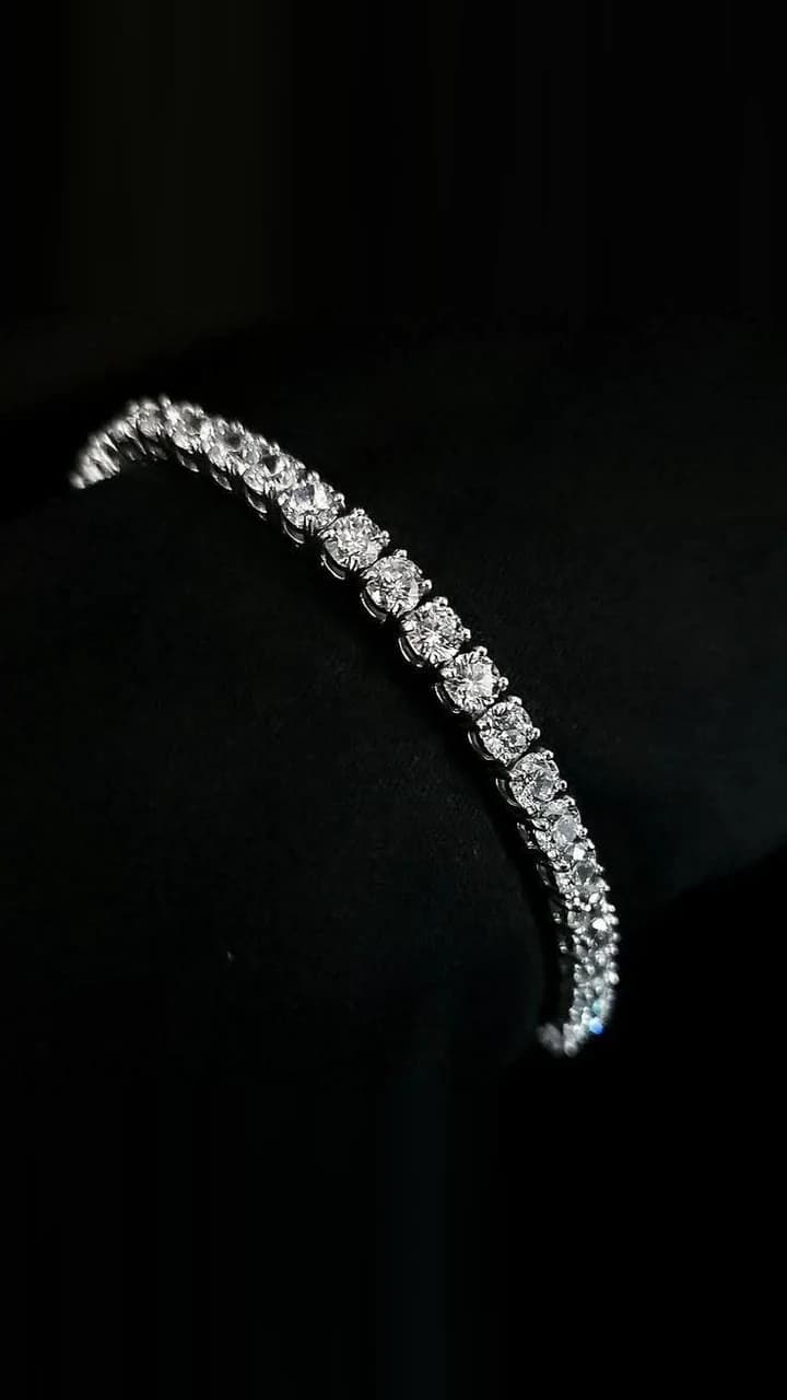 A diamond tennis bracelet, one continuous run of claw-set brilliants, photographed on black.