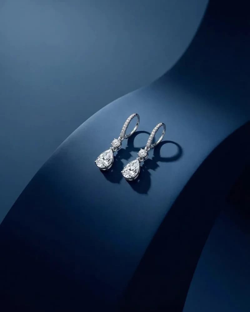 A pair of small diamond pear-drop earrings on a fine hoop.