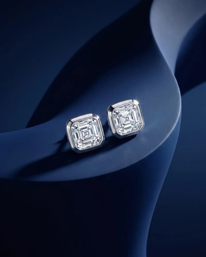 A pair of Asscher-cut diamond studs on blue.