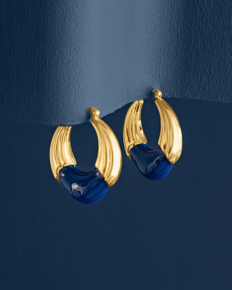 A pair of polished gold hoop earrings set with cushion sapphires.