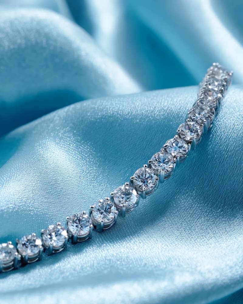 A graduated diamond tennis bracelet on pale blue silk.