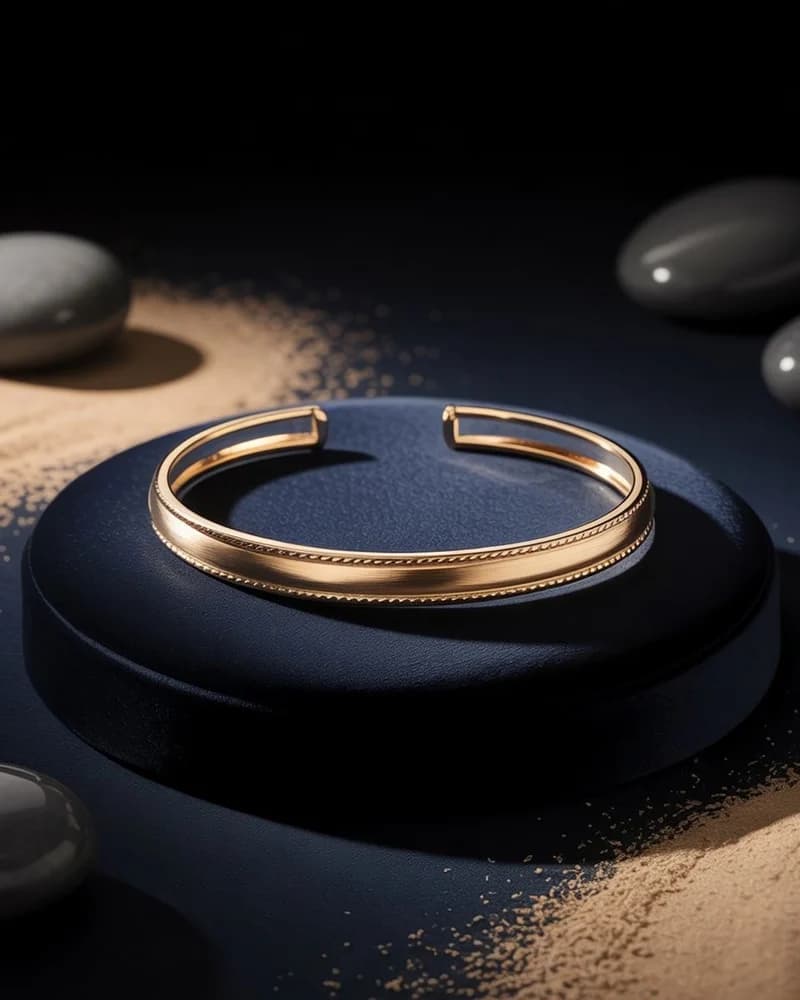 A plain polished yellow gold open cuff on dark stone.