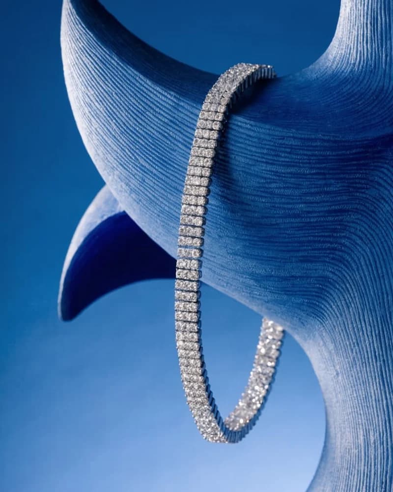 A single-row diamond line bracelet curved on blue silk.